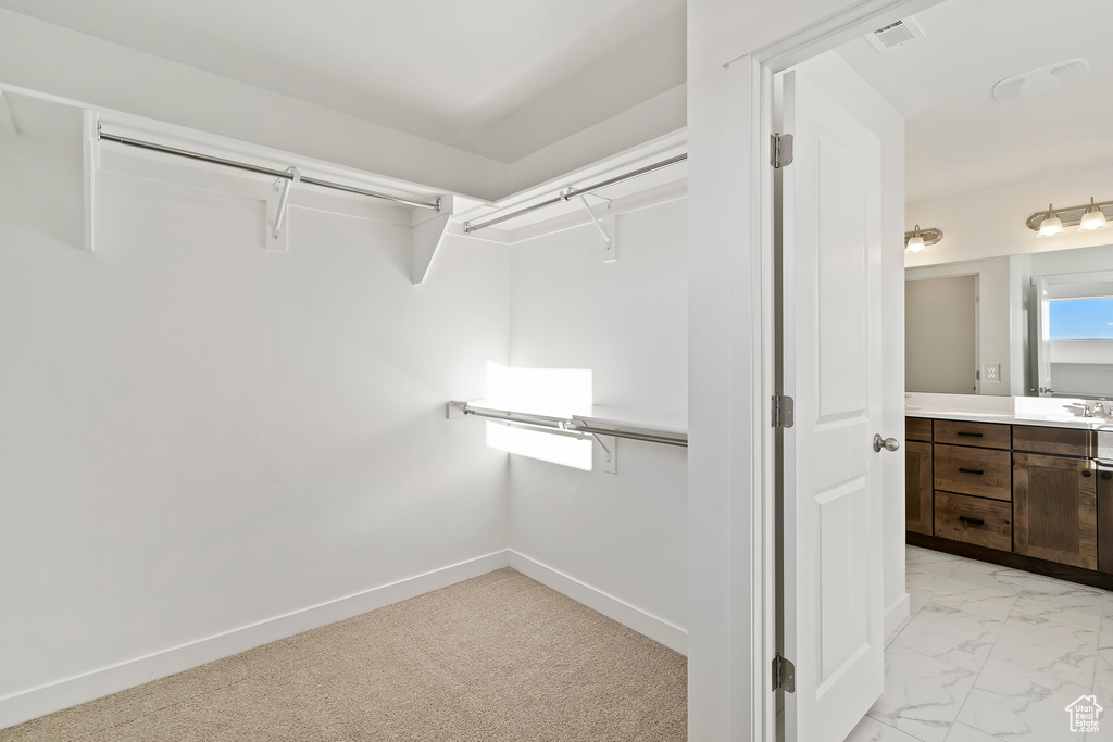 Walk in closet with light marble finish flooring and a sink