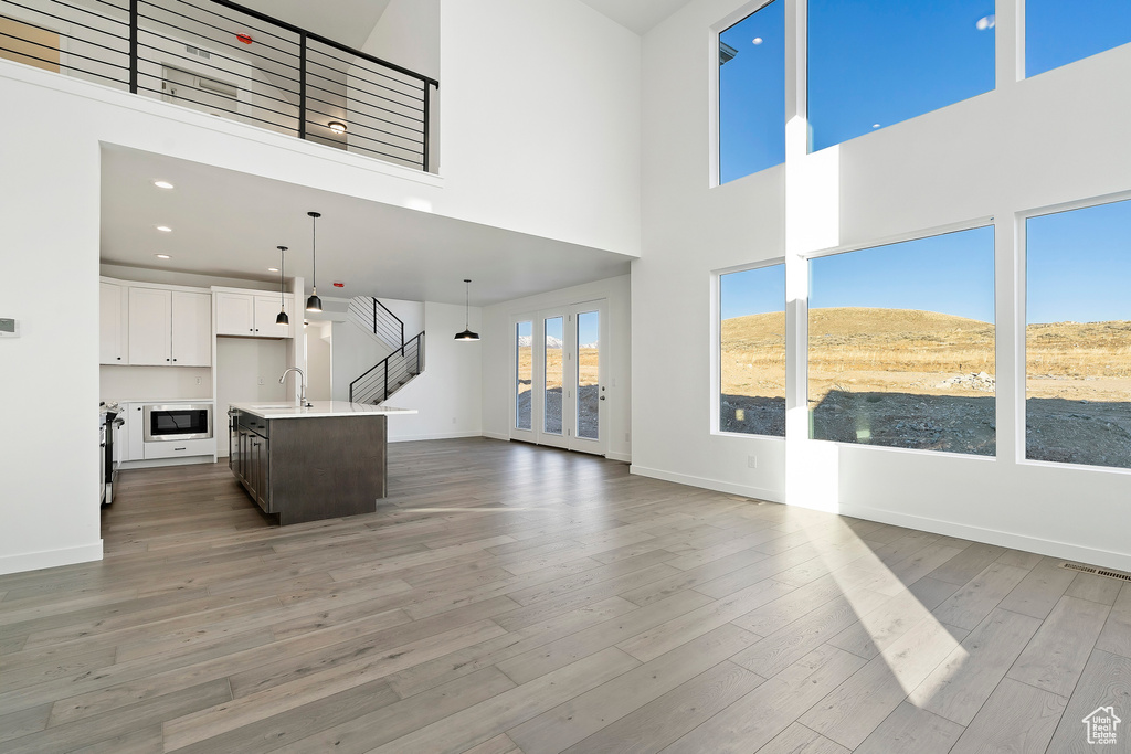 Unfurnished living room with a towering ceiling, light wood-style flooring, and recessed lighting