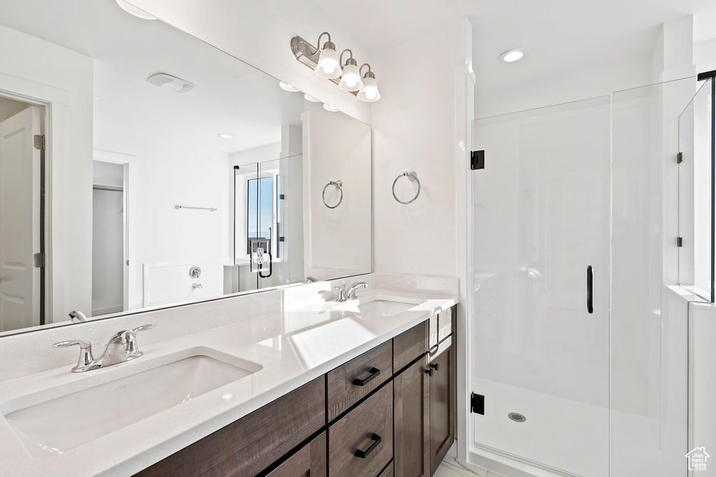 Bathroom with double vanity, a shower stall, and recessed lighting