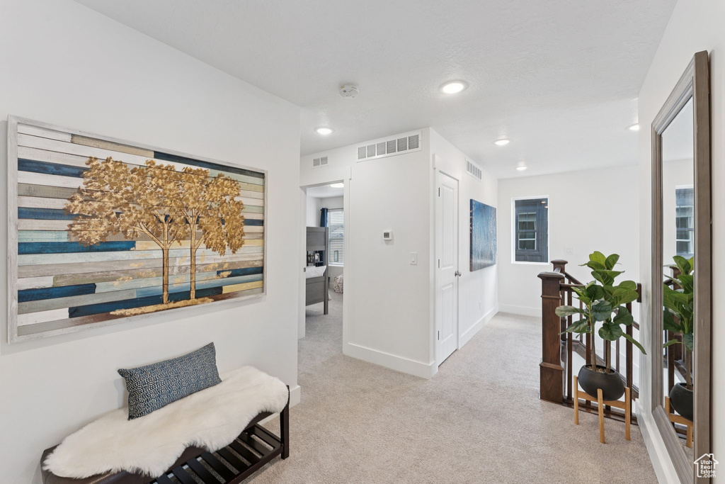 Corridor with light colored carpet and recessed lighting