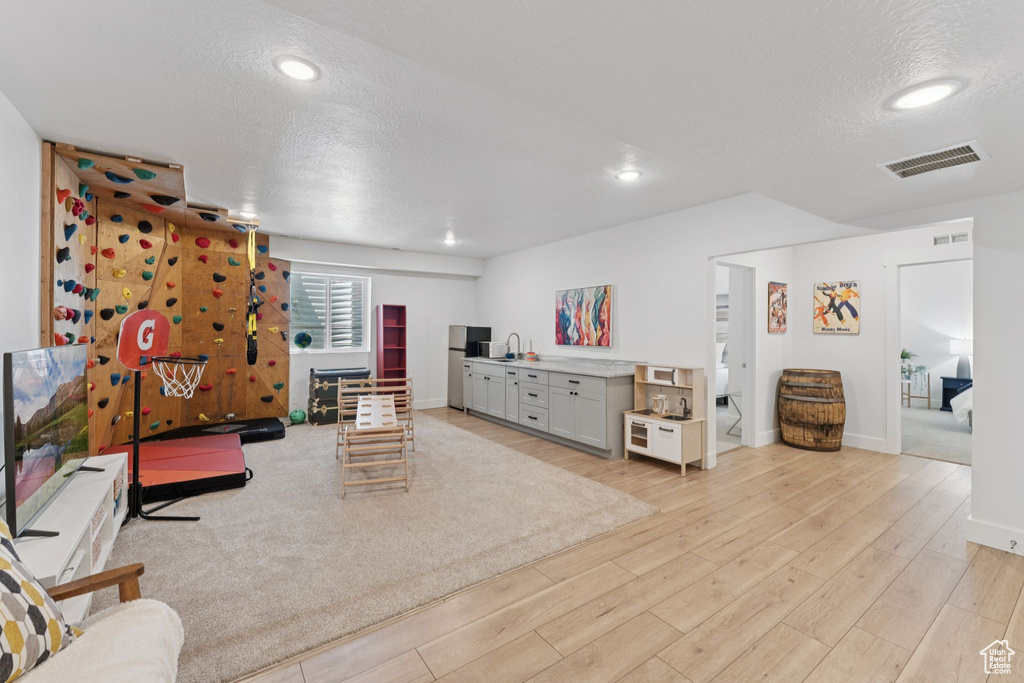 Living room with light wood finished floors, a textured ceiling, and recessed lighting