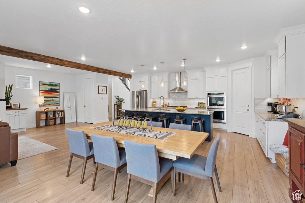 Dining room featuring recessed lighting, light wood finished floors, and beamed ceiling