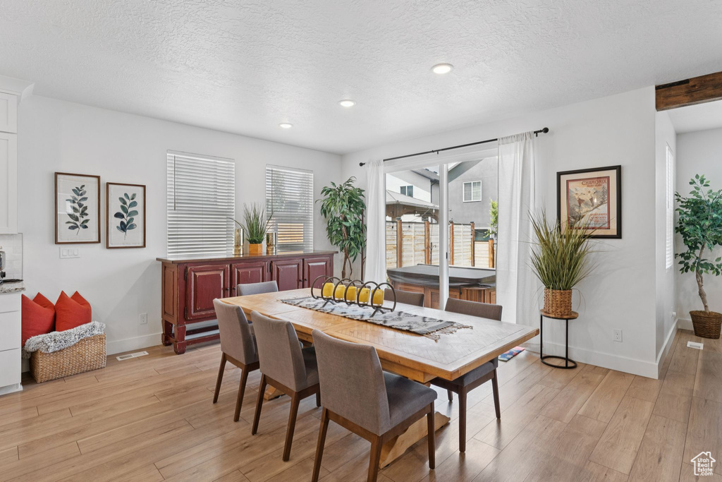 Dining space with light wood finished floors, a textured ceiling, and recessed lighting