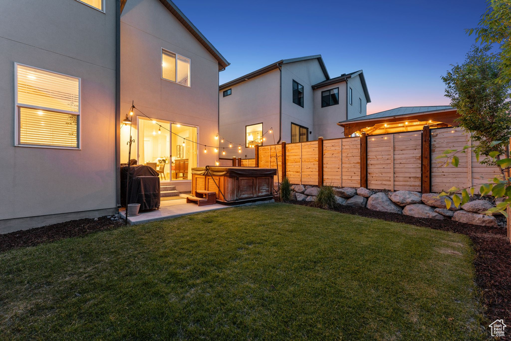 Fenced backyard with a hot tub and a patio