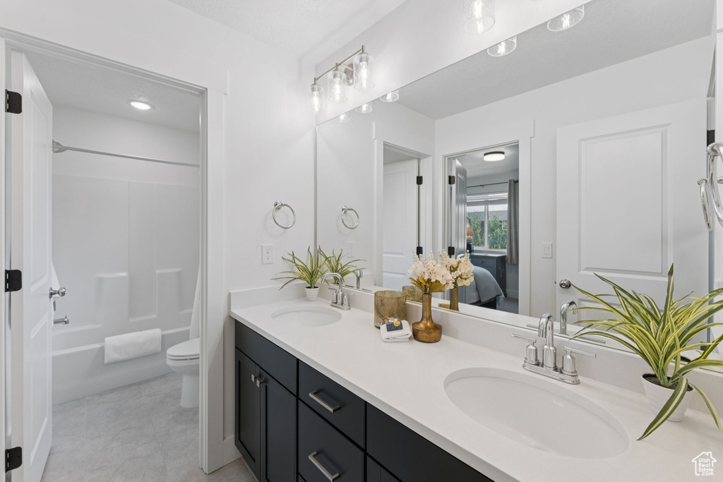 Bathroom with double vanity, tile patterned floors, washtub / shower combination, and ensuite bath
