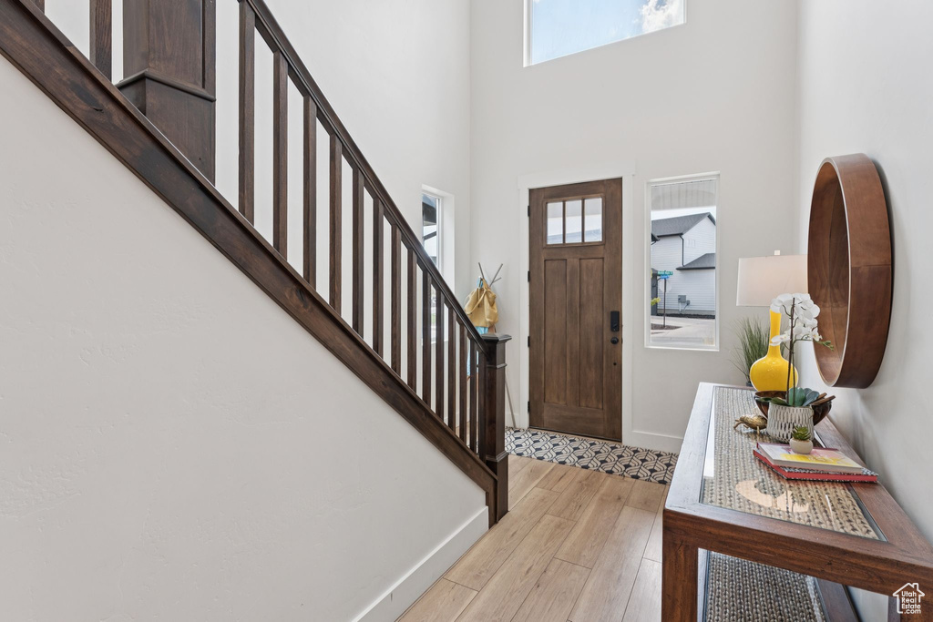 Entrance foyer with stairs, light wood finished floors, and a towering ceiling