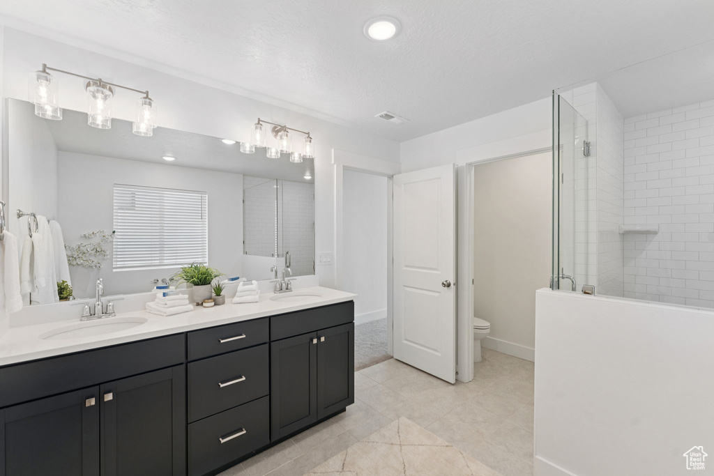 Bathroom with double vanity, a tile shower, and tile patterned floors