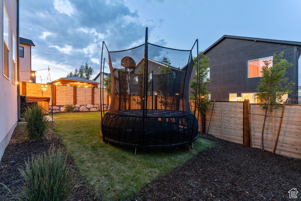 Fenced backyard featuring a trampoline