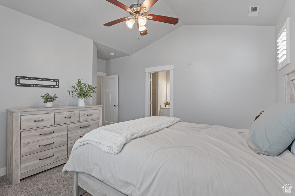 Bedroom featuring lofted ceiling, light carpet, ensuite bathroom, and a ceiling fan