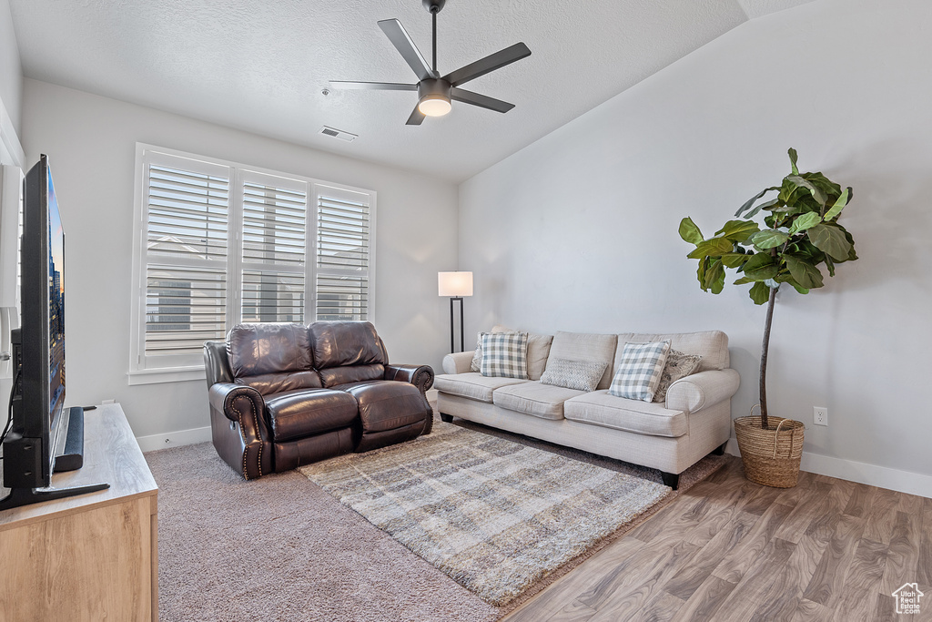 Living area featuring lofted ceiling, ceiling fan, a textured ceiling, and wood finished floors