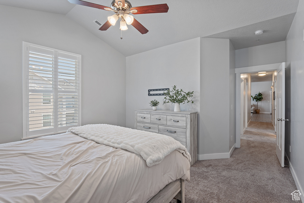 Bedroom with light colored carpet, lofted ceiling, and ceiling fan