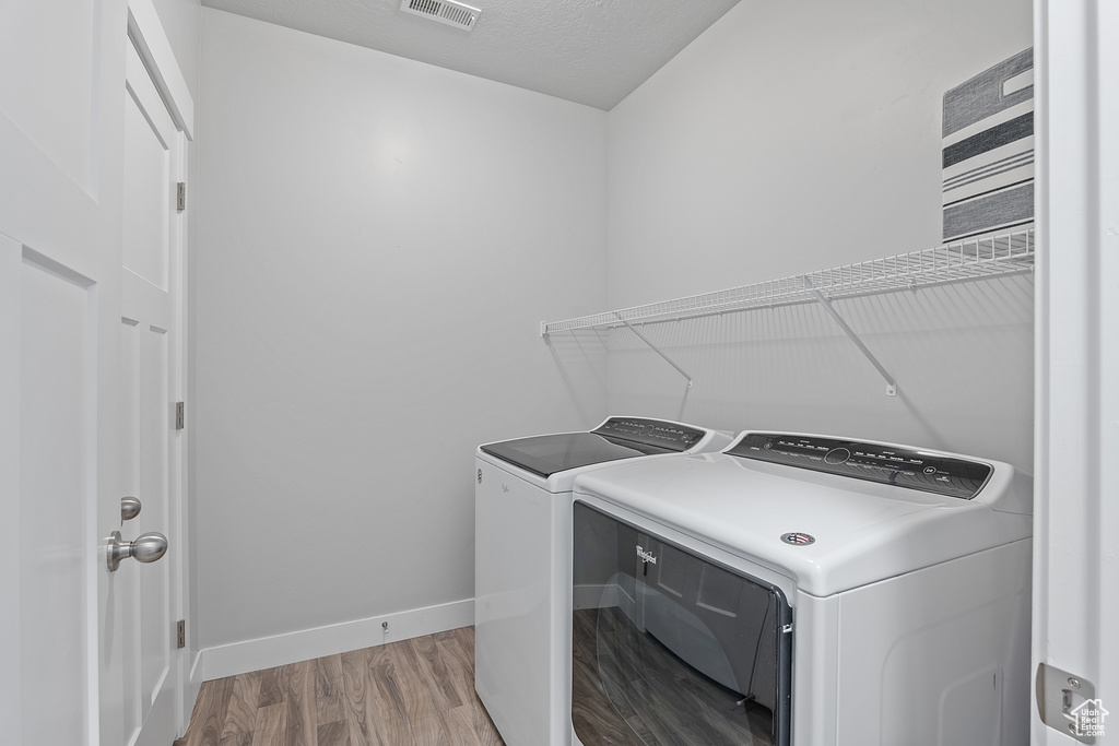 Laundry area featuring washer and clothes dryer and wood finished floors