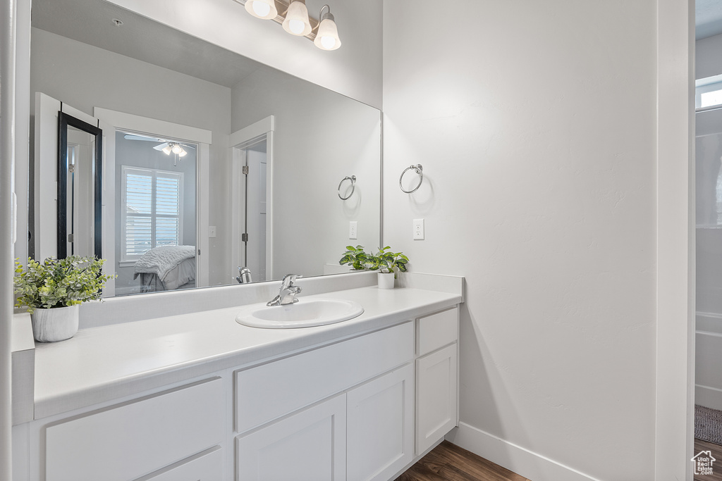 Ensuite bathroom featuring vanity, wood finished floors, and healthy amount of natural light