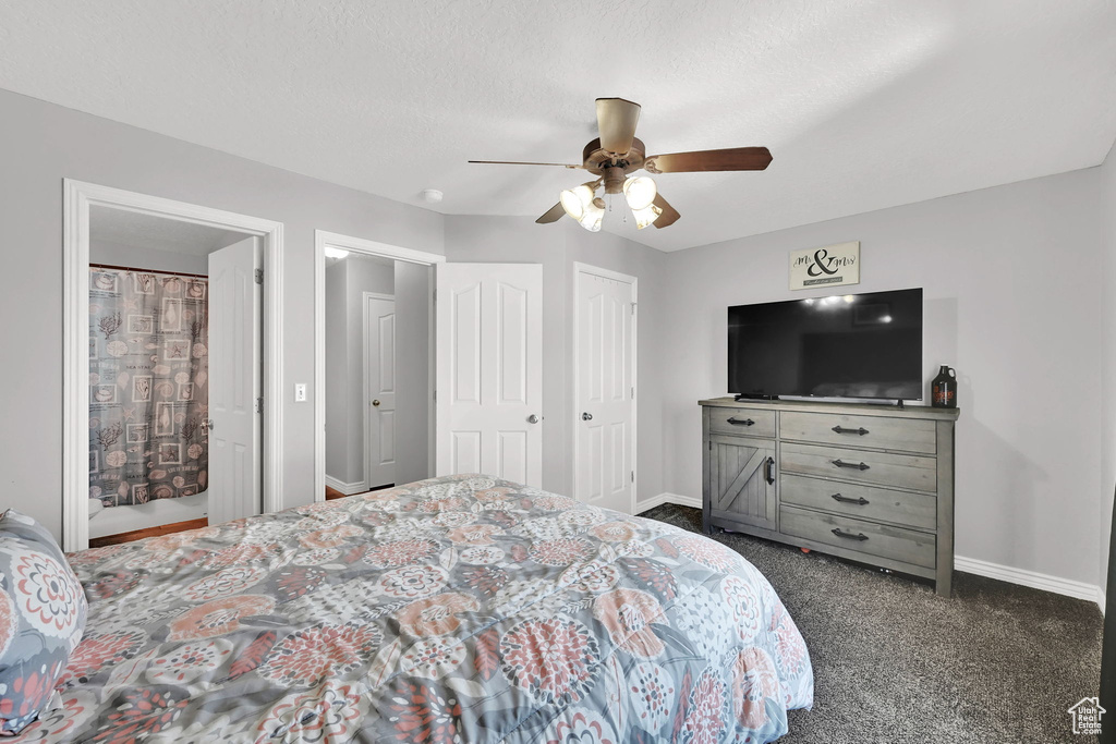 Bedroom with dark colored carpet, a ceiling fan, and two closets
