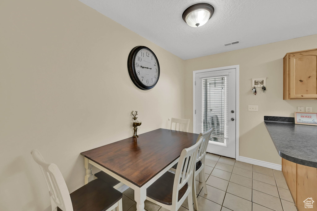 Dining space featuring light tile patterned floors and a textured ceiling