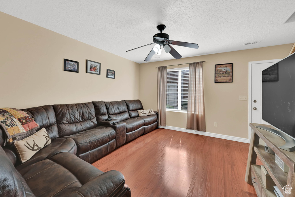 Living area featuring ceiling fan, wood finished floors, and a textured ceiling