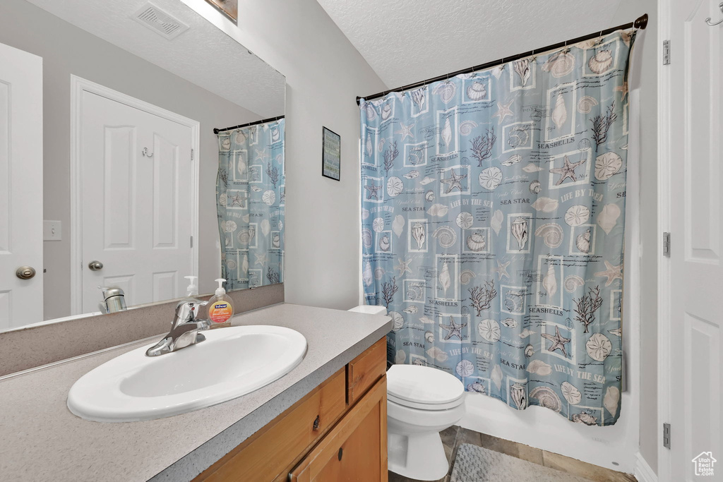 Full bathroom with vanity, tile patterned flooring, and a textured ceiling