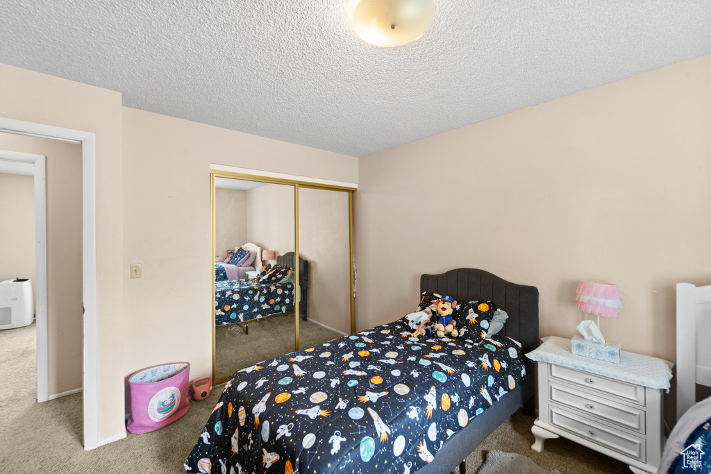 Carpeted bedroom with a closet and a textured ceiling