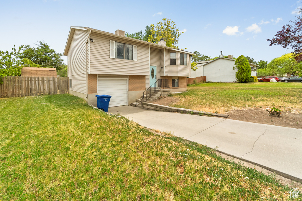 Split foyer home with a garage, driveway, a chimney, and brick siding