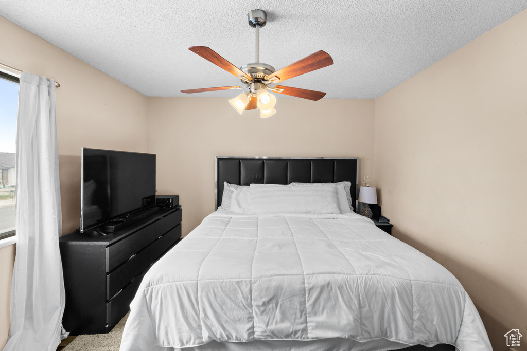 Bedroom with ceiling fan and a textured ceiling