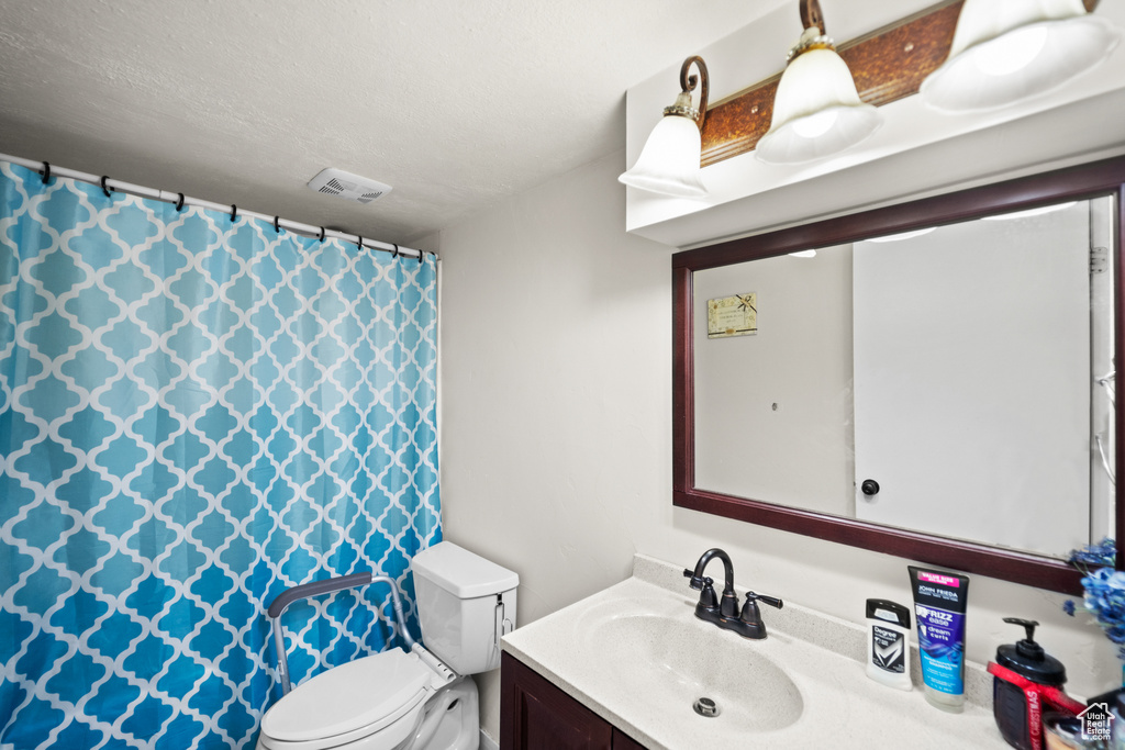 Full bath with vanity, curtained shower, and a textured ceiling