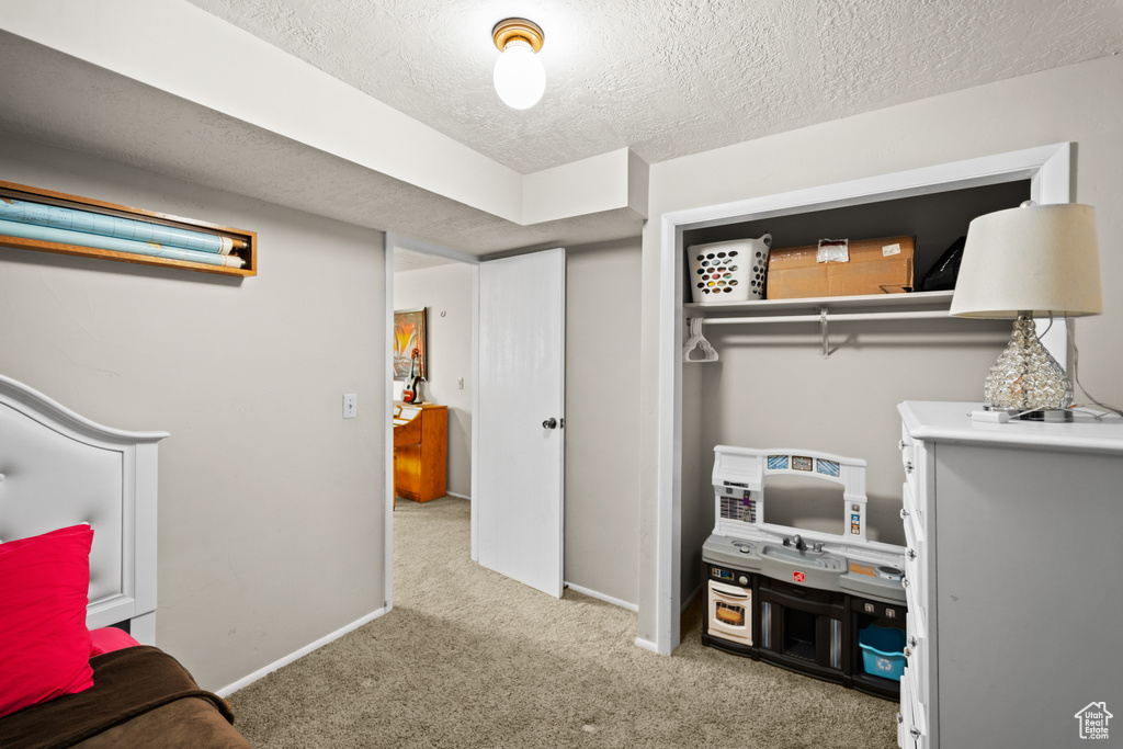 Bedroom with carpet floors, a textured ceiling, and a closet