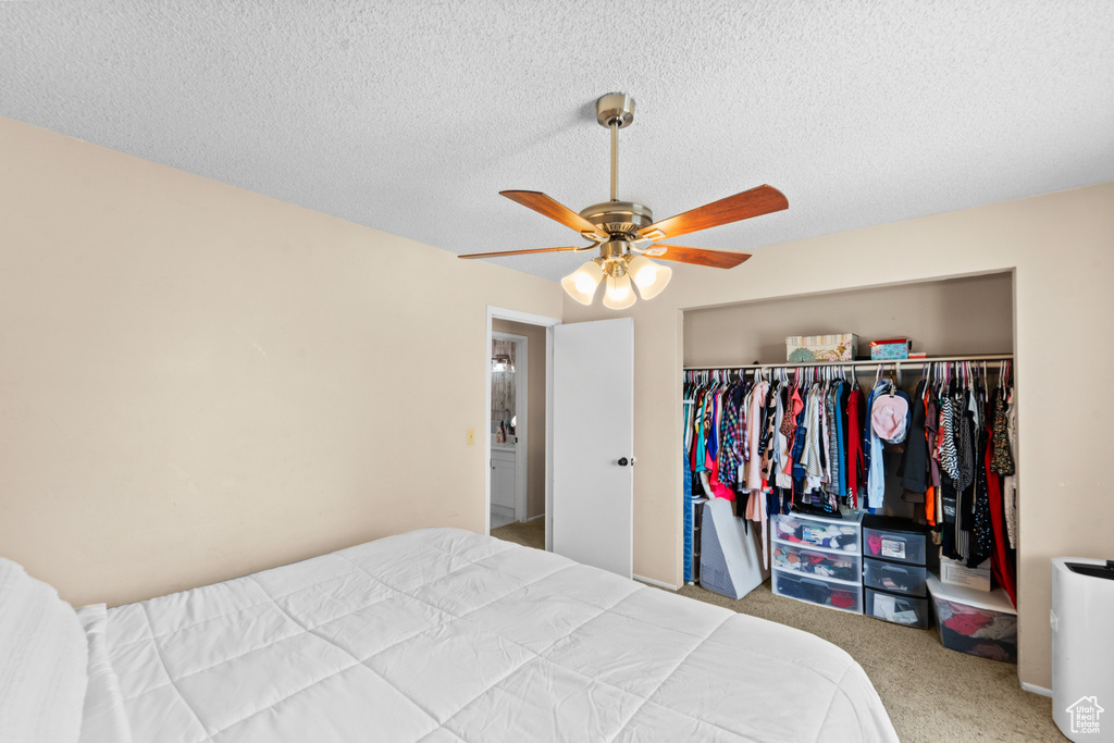 Bedroom with a closet, carpet flooring, a ceiling fan, and a textured ceiling