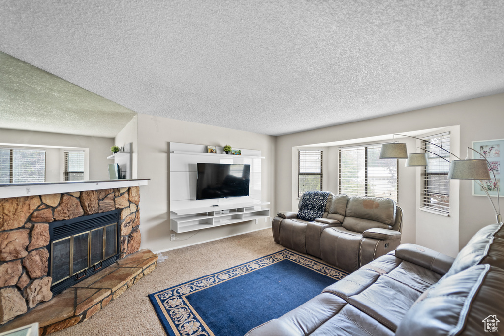 Living room with carpet flooring, a textured ceiling, and a fireplace