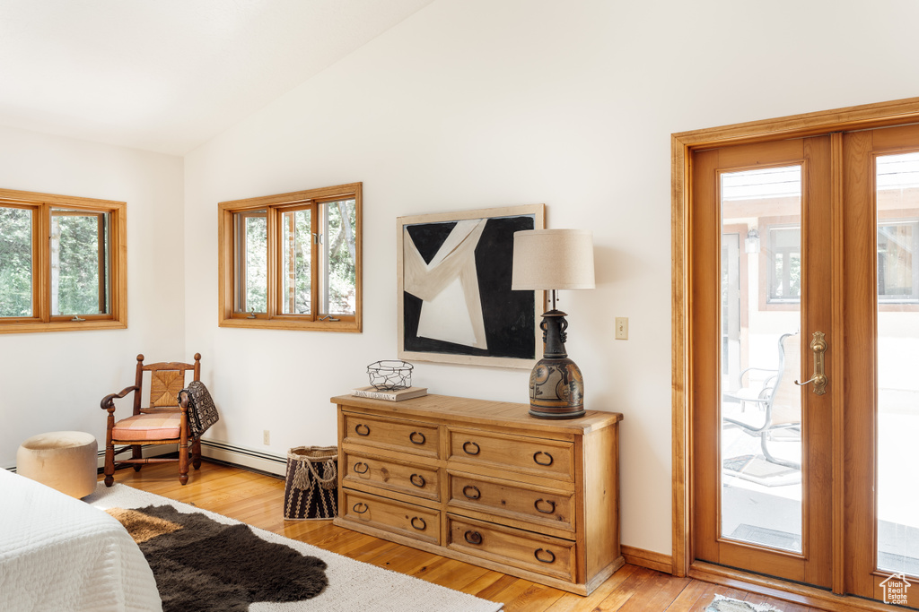 Bedroom with access to exterior, light wood-type flooring, lofted ceiling, and a baseboard heating unit