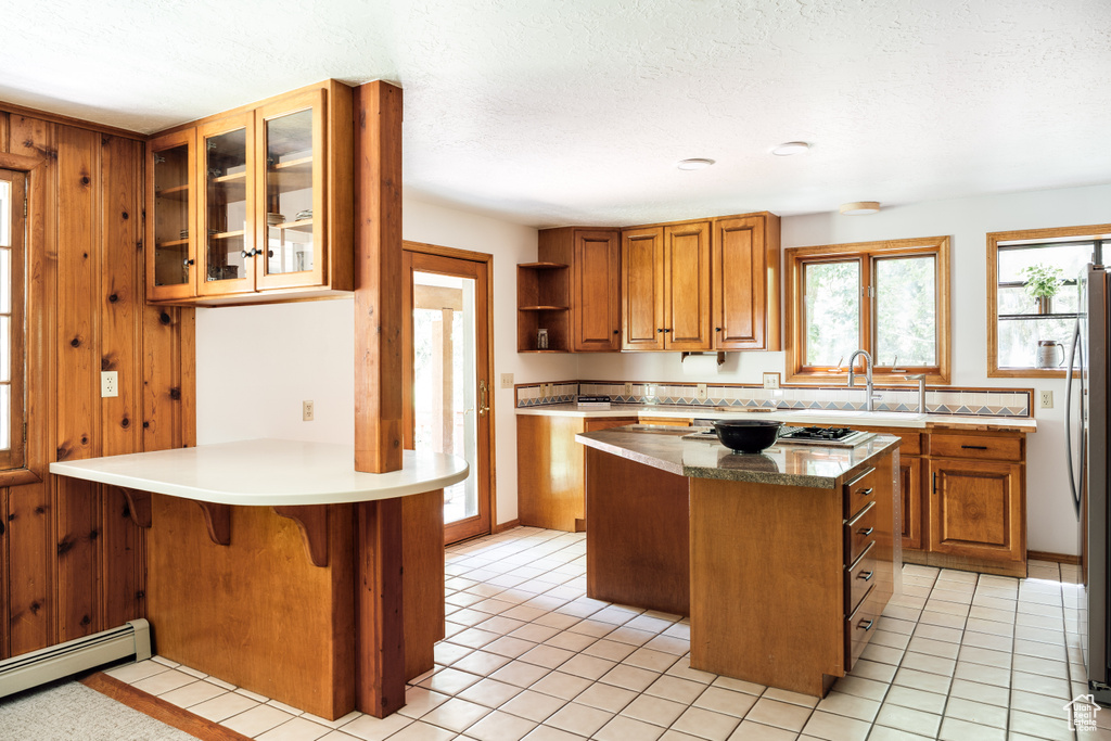 Kitchen featuring a baseboard heating unit, brown cabinets, open shelves, a peninsula, and a textured ceiling