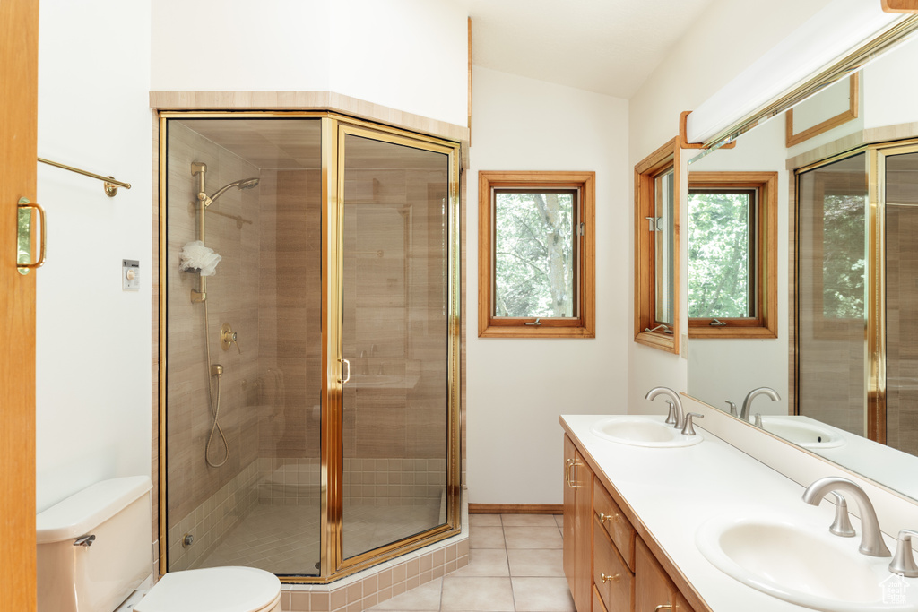 Bathroom with double vanity, tile patterned floors, a stall shower, and lofted ceiling