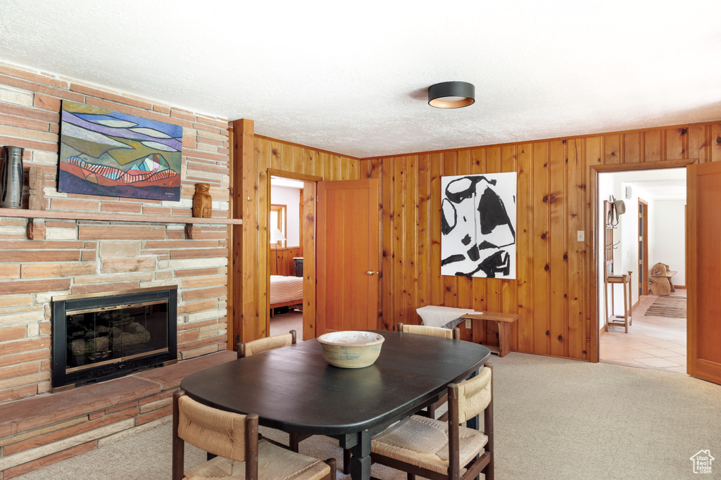 Dining area with wood walls, carpet flooring, and a fireplace