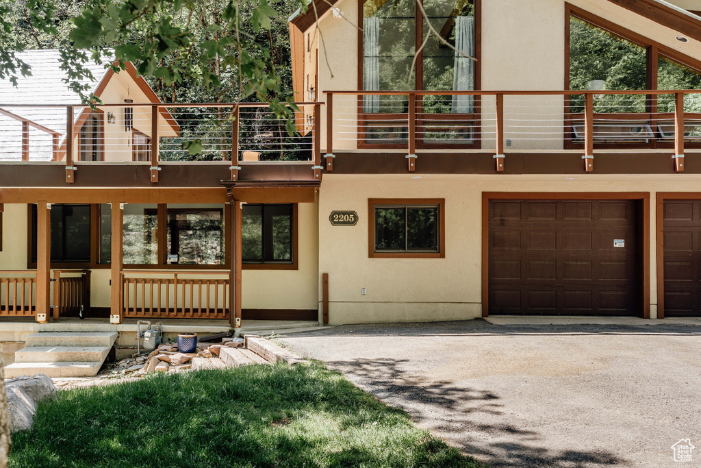 View of front facade featuring a balcony, stucco siding, and driveway
