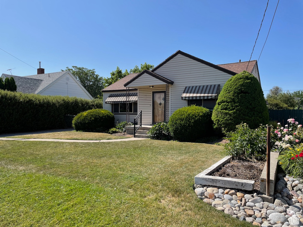 Bungalow featuring a front lawn and roof with shingles