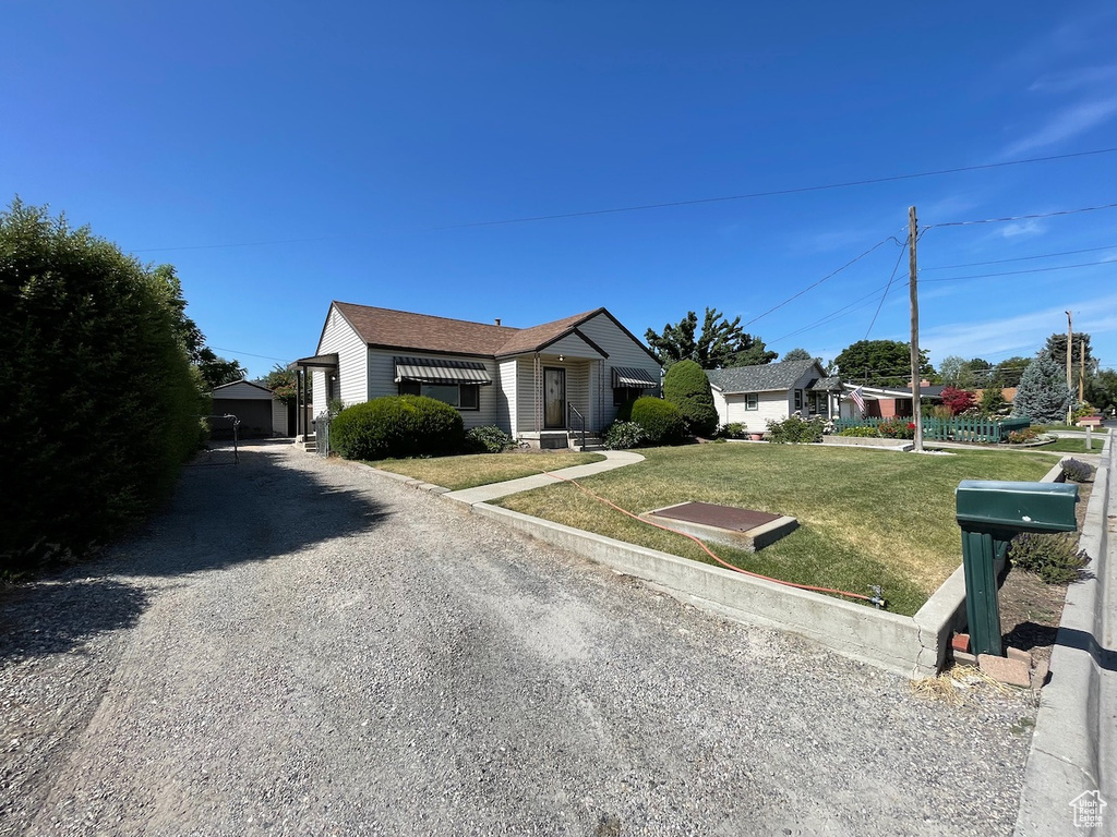 Ranch-style house featuring a front yard and gravel driveway