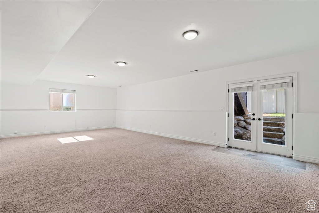 Carpeted empty room with french doors and baseboards