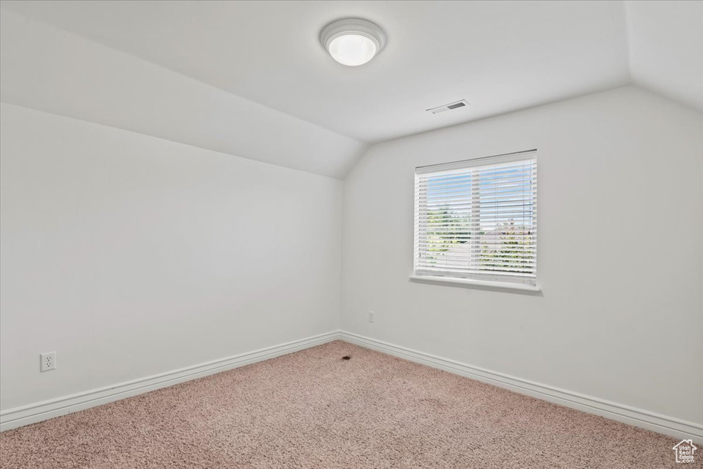 Additional living space featuring vaulted ceiling and carpet flooring
