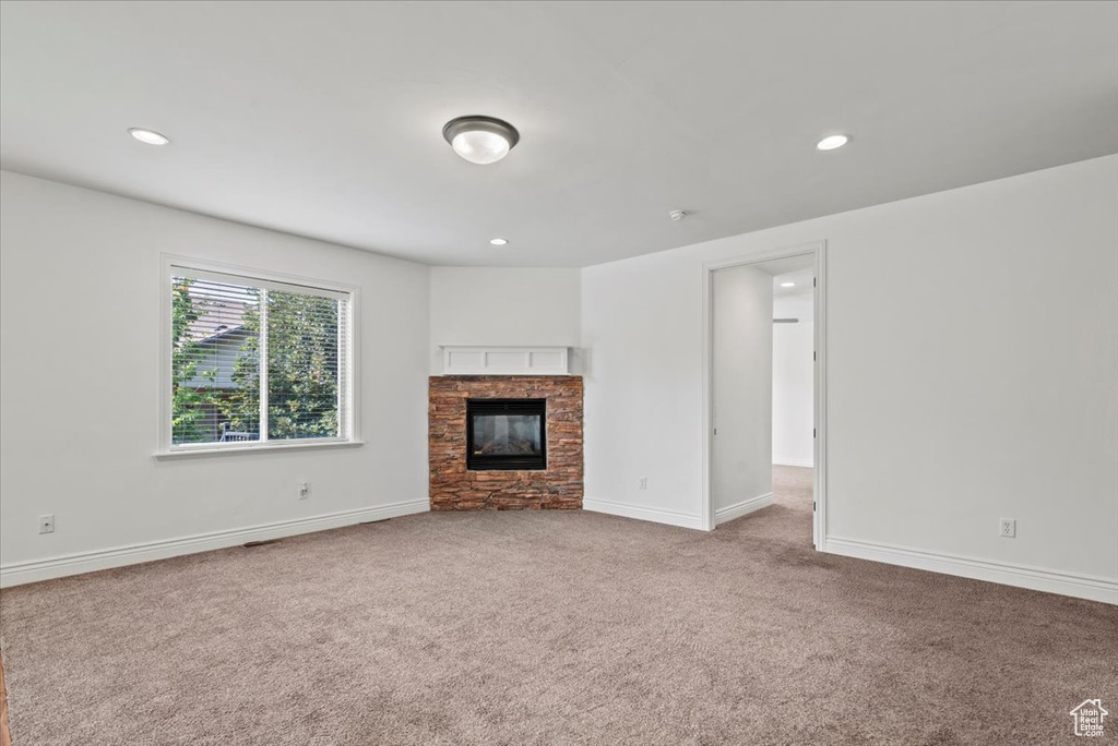 Unfurnished living room featuring carpet floors, a stone fireplace, and recessed lighting