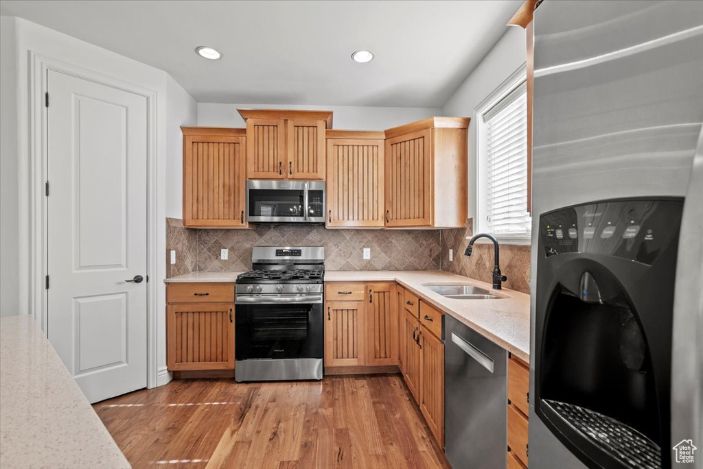 Kitchen with appliances with stainless steel finishes, light wood finished floors, backsplash, and recessed lighting
