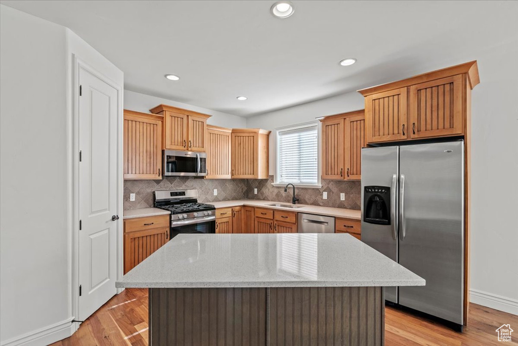 Kitchen with stainless steel appliances, backsplash, light wood finished floors, and recessed lighting