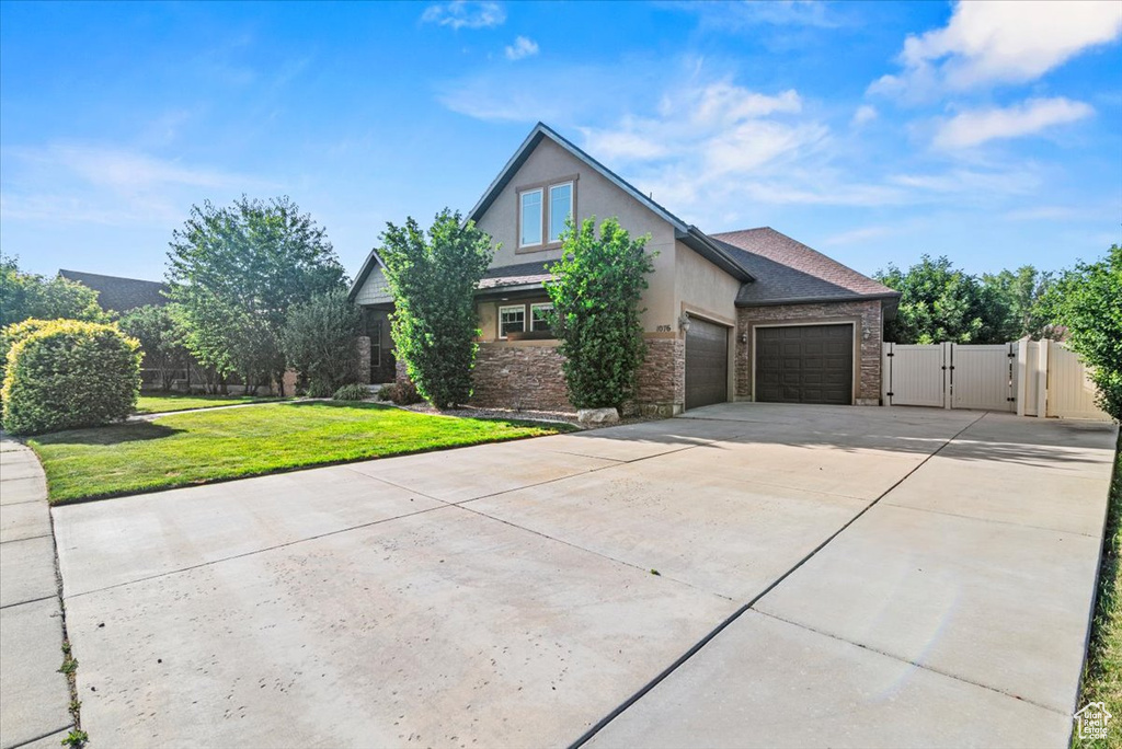 View of front of property featuring a gate, driveway, a garage, stucco siding, and stone siding