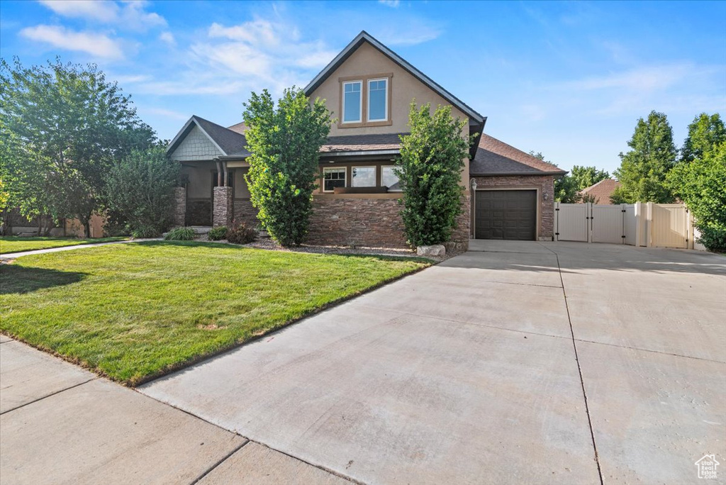 View of front facade featuring concrete driveway, a gate, stone siding, an attached garage, and stucco siding