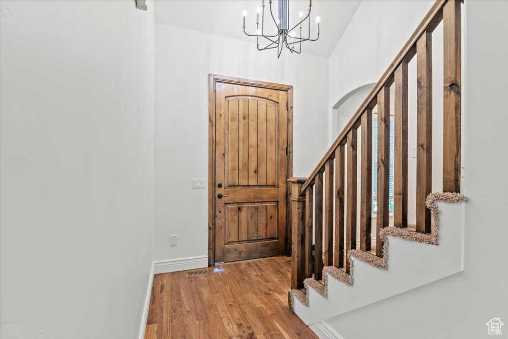 Entryway featuring wood finished floors, stairway, a chandelier, and high vaulted ceiling