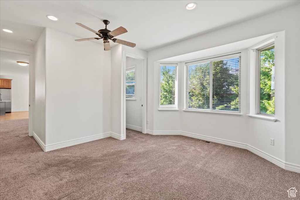 Spare room with light carpet, healthy amount of natural light, a ceiling fan, and recessed lighting