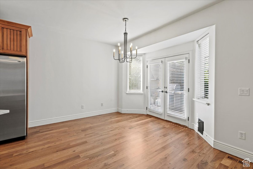 Unfurnished dining area with a chandelier and light wood-style floors