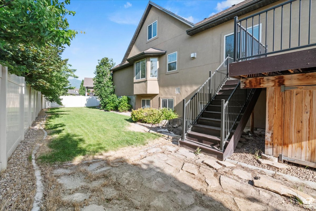 Rear view of property featuring stucco siding, a fenced backyard, and stairway