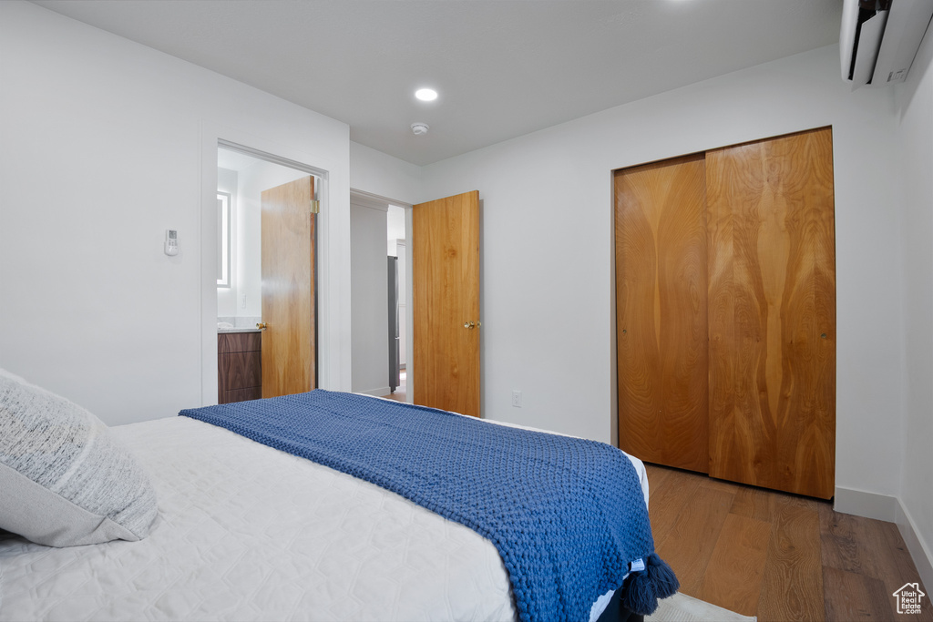 Bedroom featuring an AC wall unit, wood finished floors, a closet, and recessed lighting