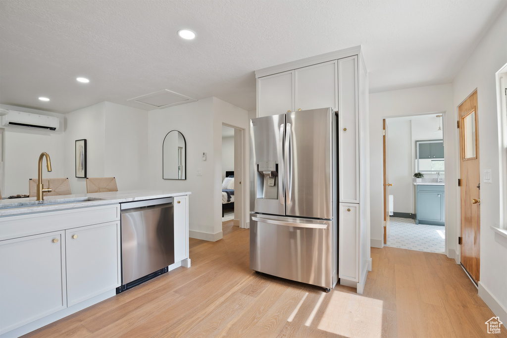Kitchen featuring stainless steel appliances, a wall mounted air conditioner, light wood finished floors, recessed lighting, and light countertops