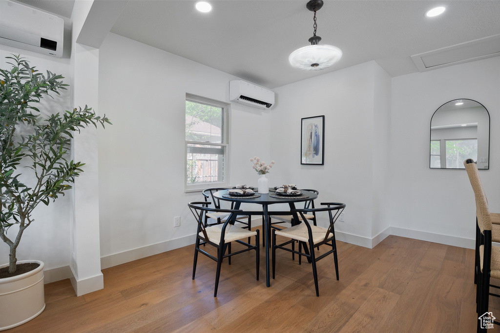 Dining space with a wall mounted AC, light wood-style flooring, plenty of natural light, and recessed lighting
