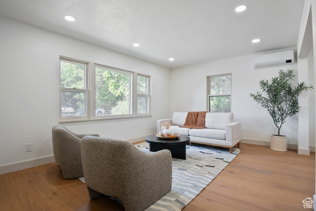 Living room with an AC wall unit, recessed lighting, and light wood finished floors